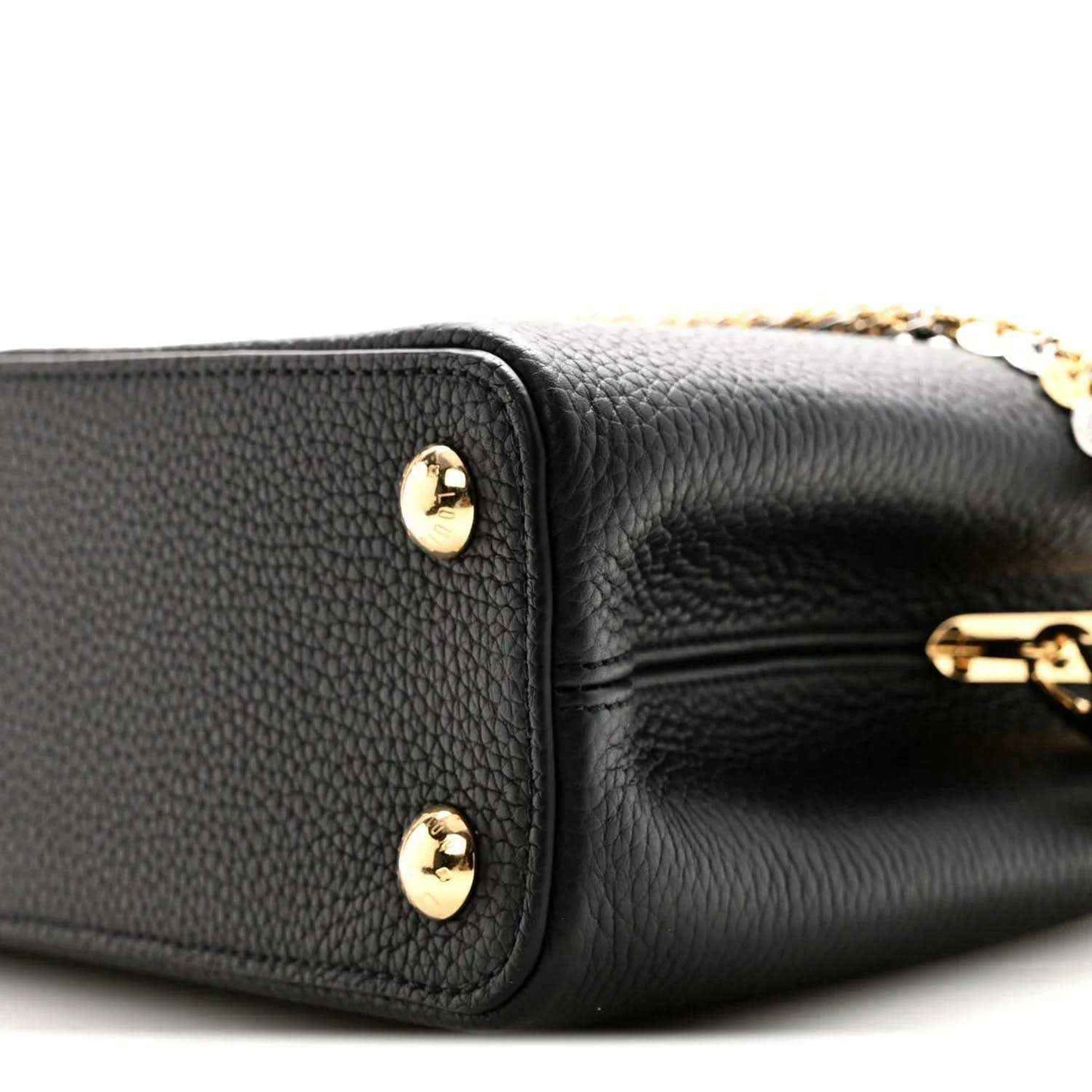 Black leather handbag corner with two gold-tone snap studs and inner zipper edge
