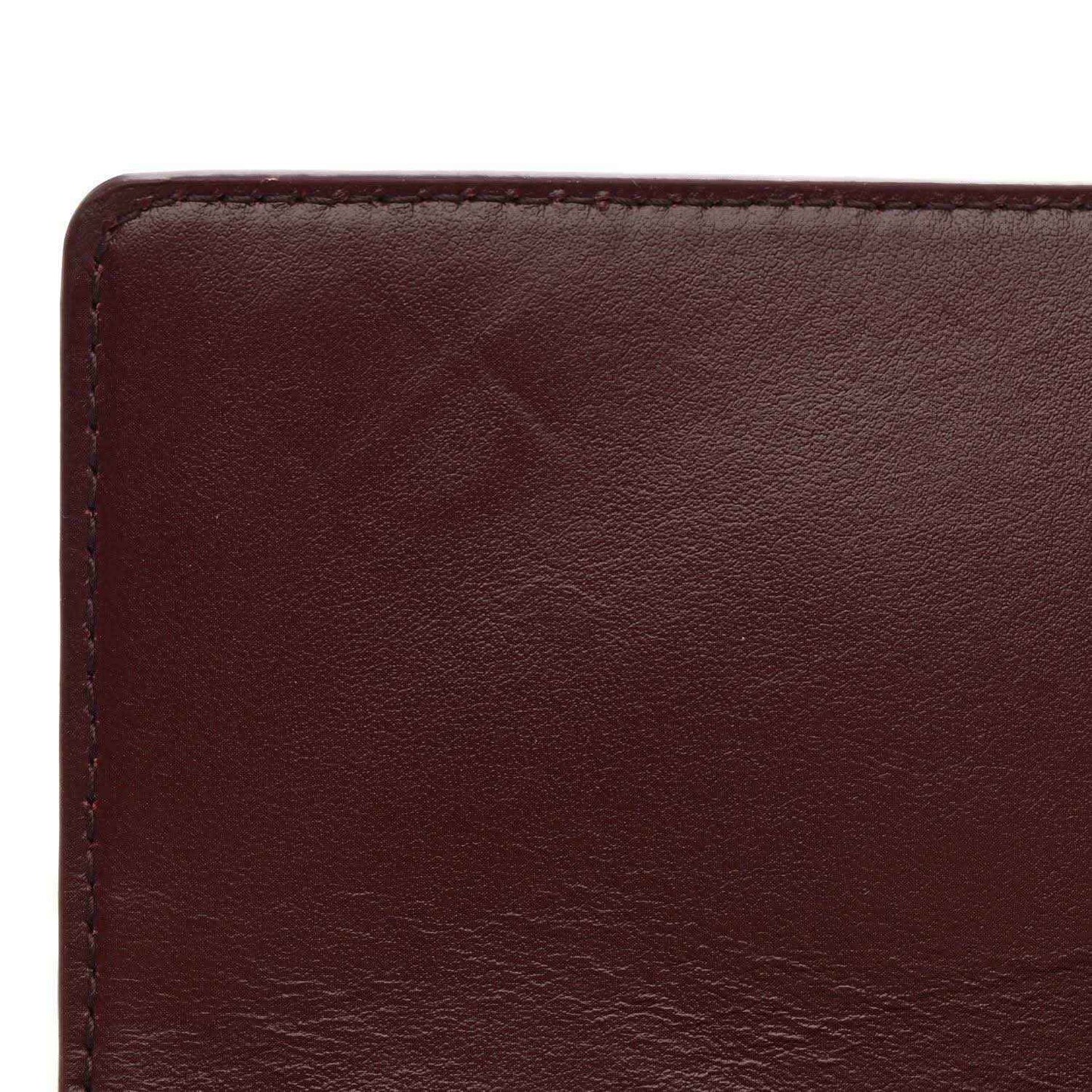 Burgundy leather clutch front panel close-up with smooth grain and stitched border