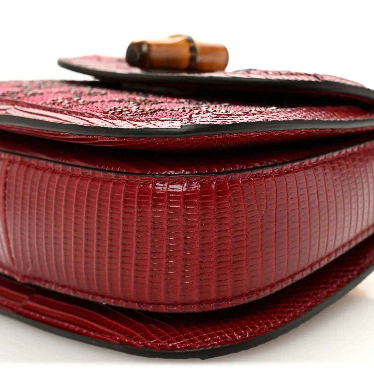 Red mini top-handle bag close-up of flap underside and ribbed texture panel detail.