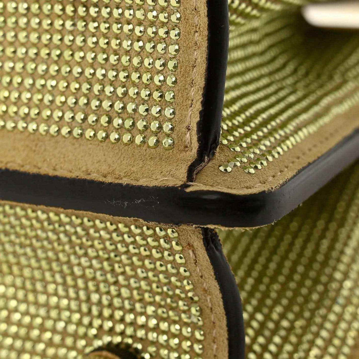 Gold crystal satchel corner detail with black leather edge and embedded studs