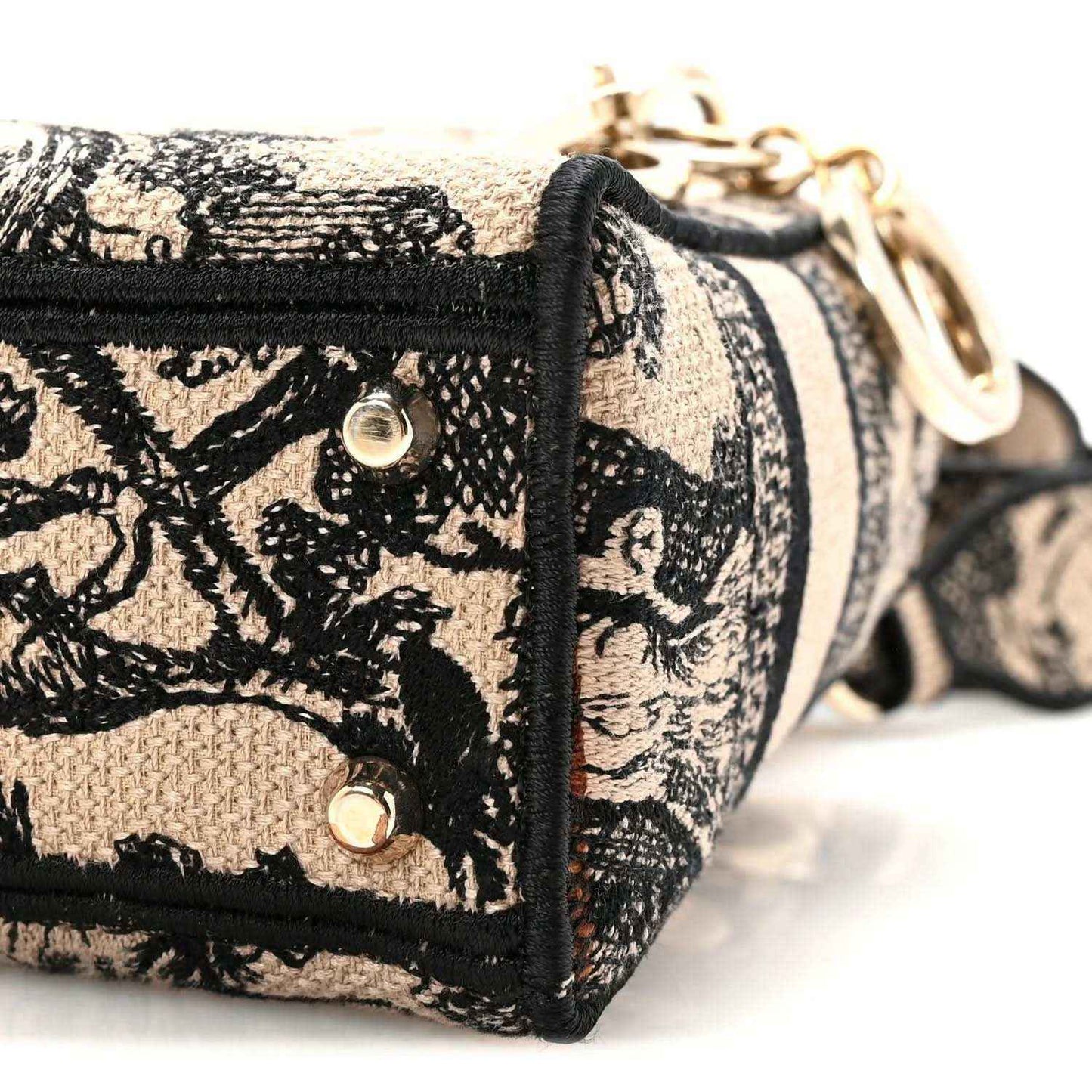 Front panel with snaps and woven strap on a black-and-cream embroidered mini handbag