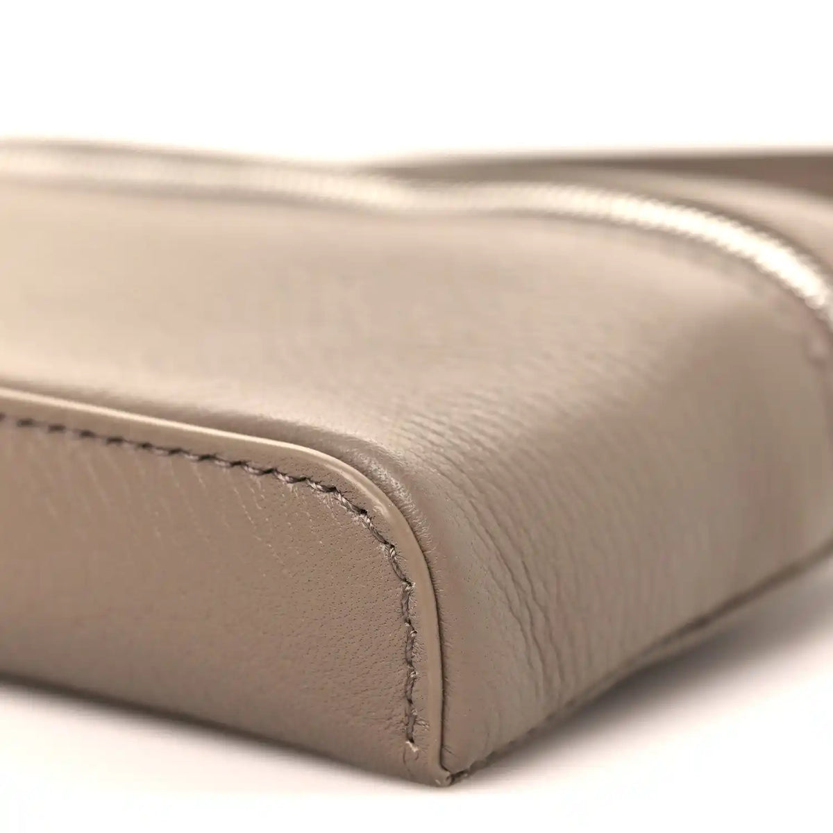 Bottom edge of a grained leather mini pouch with rounded corner seam
