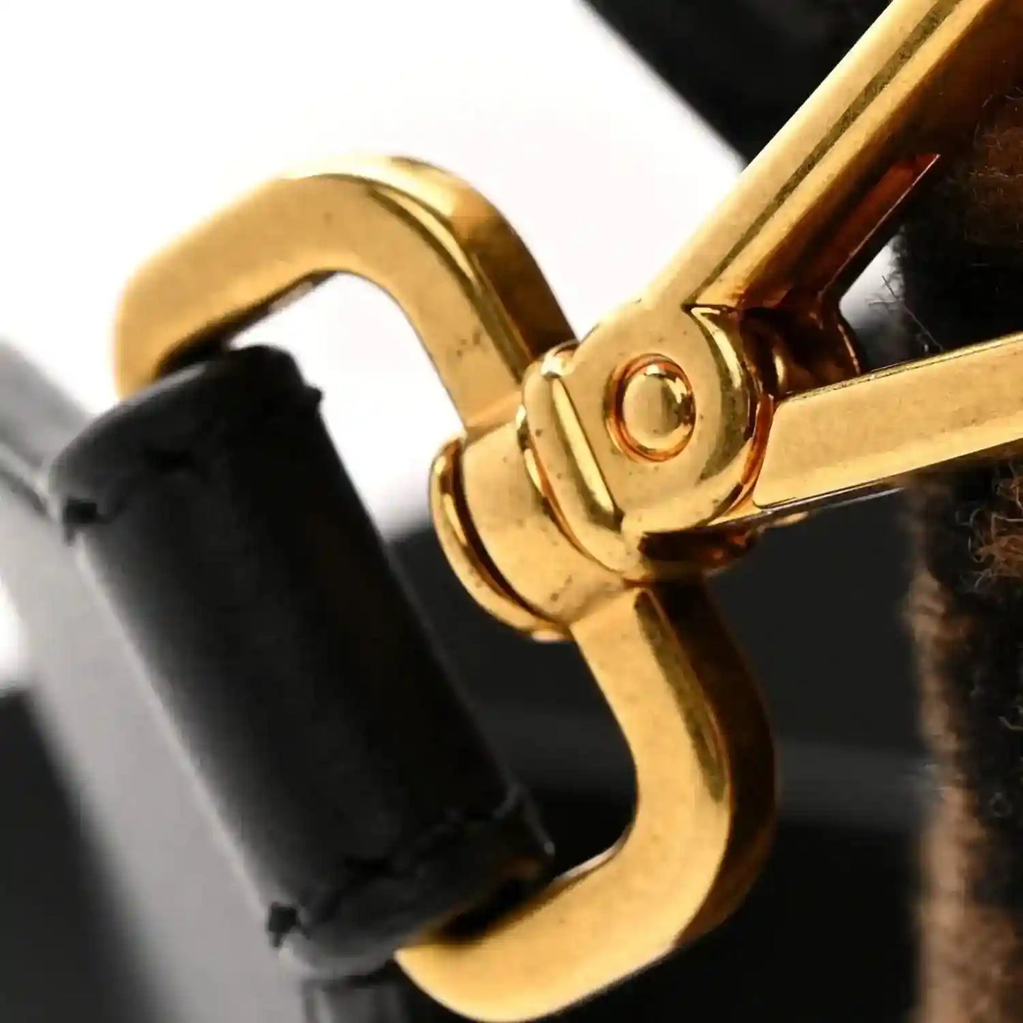 Gold-tone clasp detail on black strap of shearling baguette bag