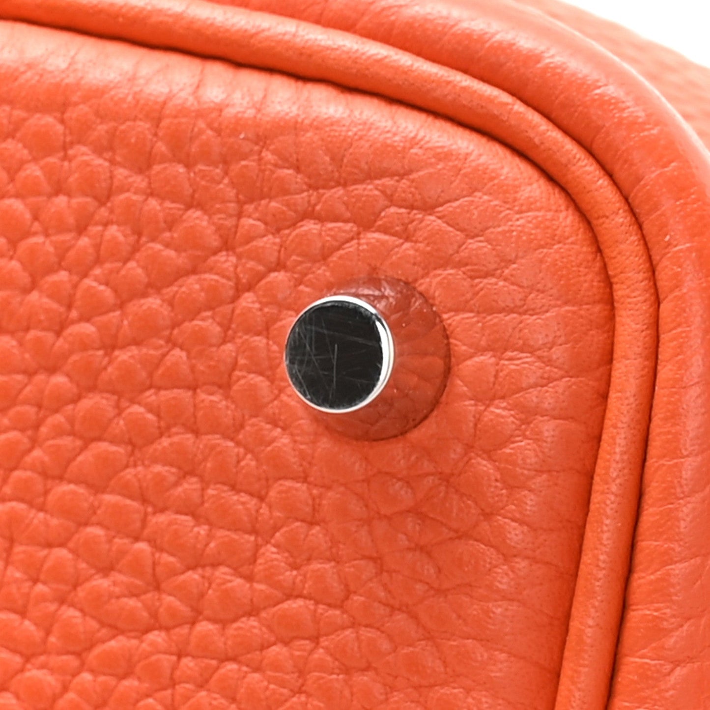 Orange pebbled leather handbag close-up of metal lock plate