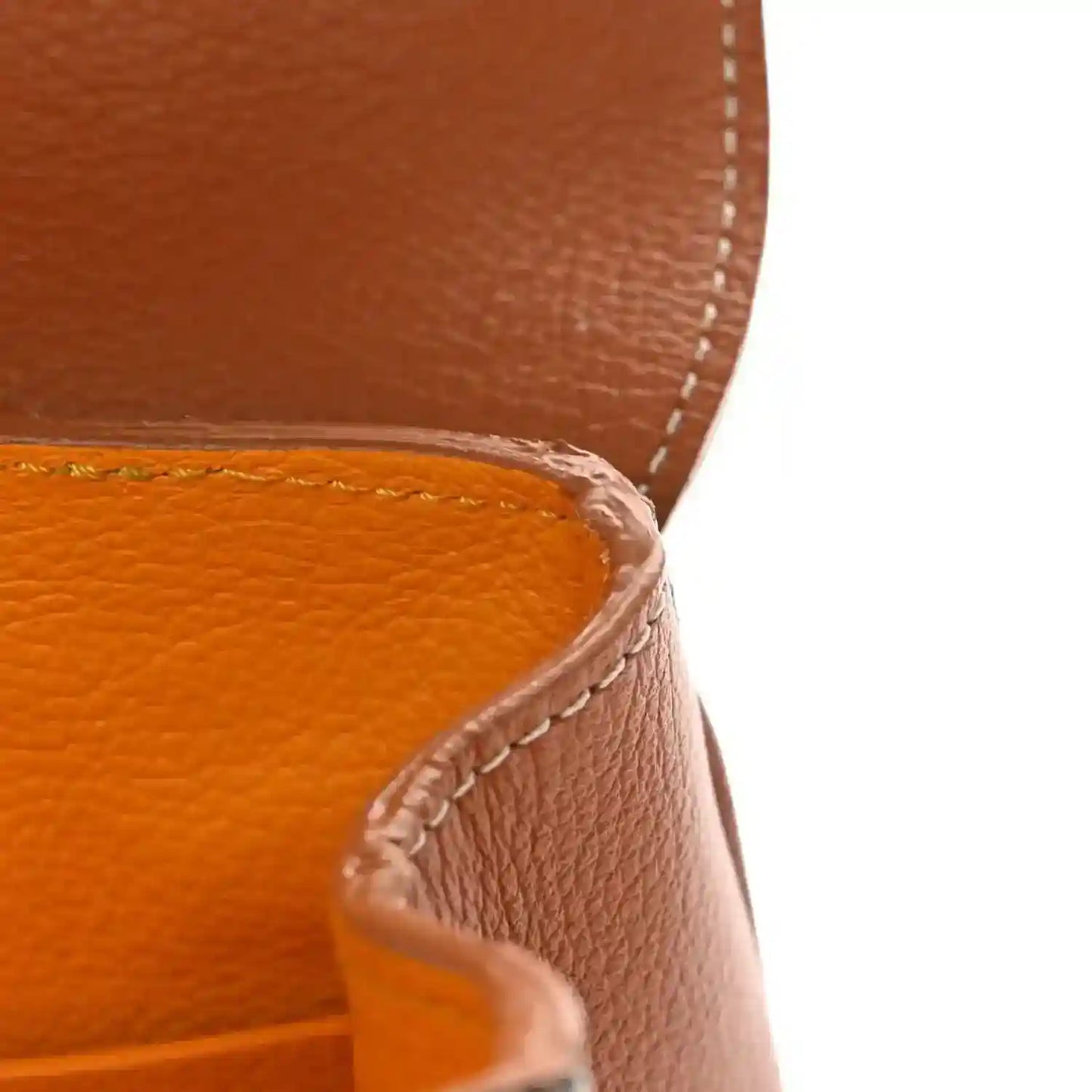 Mini shoulder bag edge with tan leather stitching and curved seam detail
