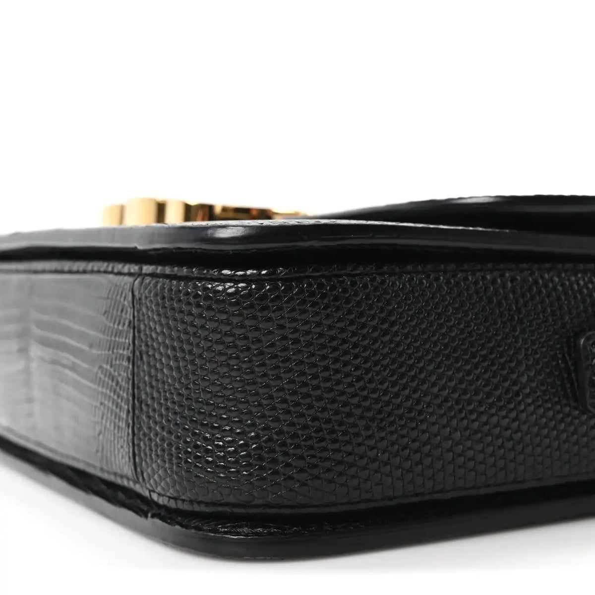 Black lizard-embossed flap bag side with gold hardware peeking