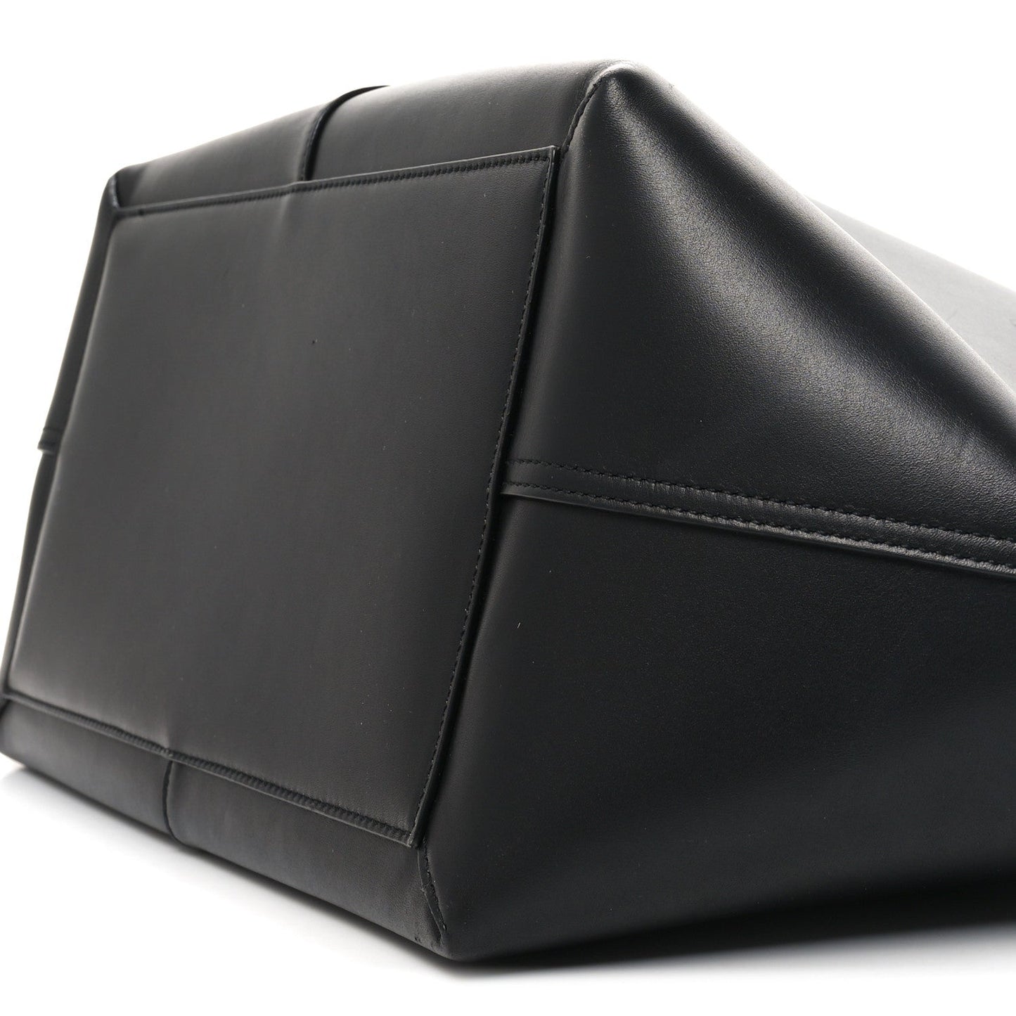 Black smooth calfskin trapezoid tote side panel with stitched seams and curved base
