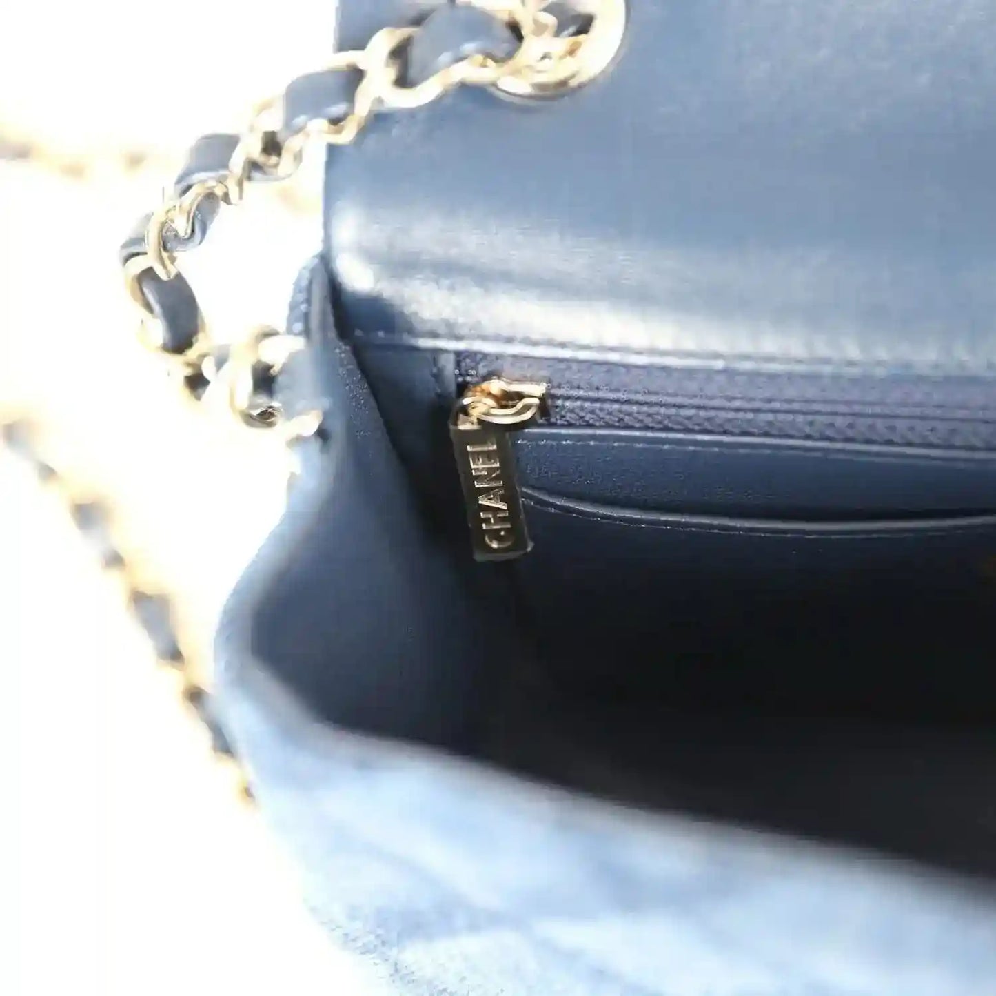 Chanel mini flap bag close-up, blue leather pocket with gold zipper pull