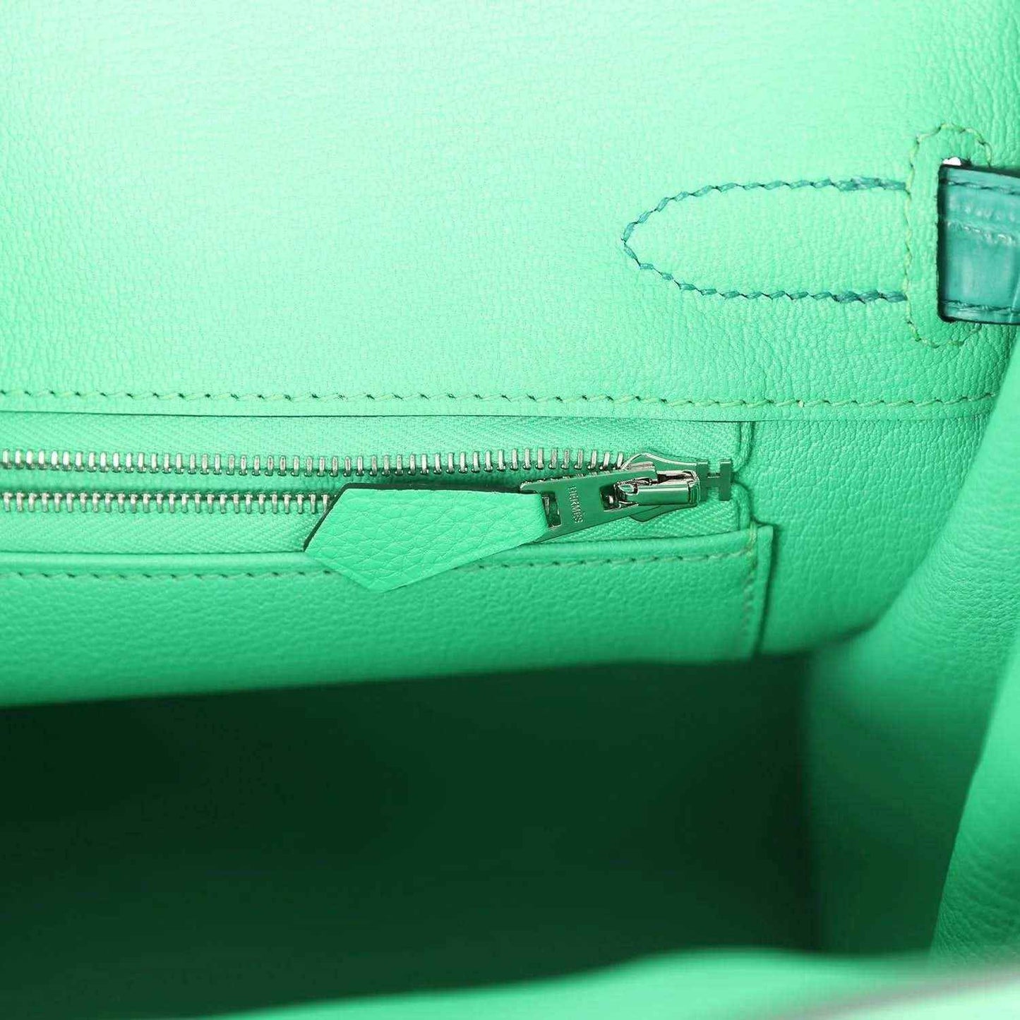 Green leather handbag interior with zipper track and small hardware detail