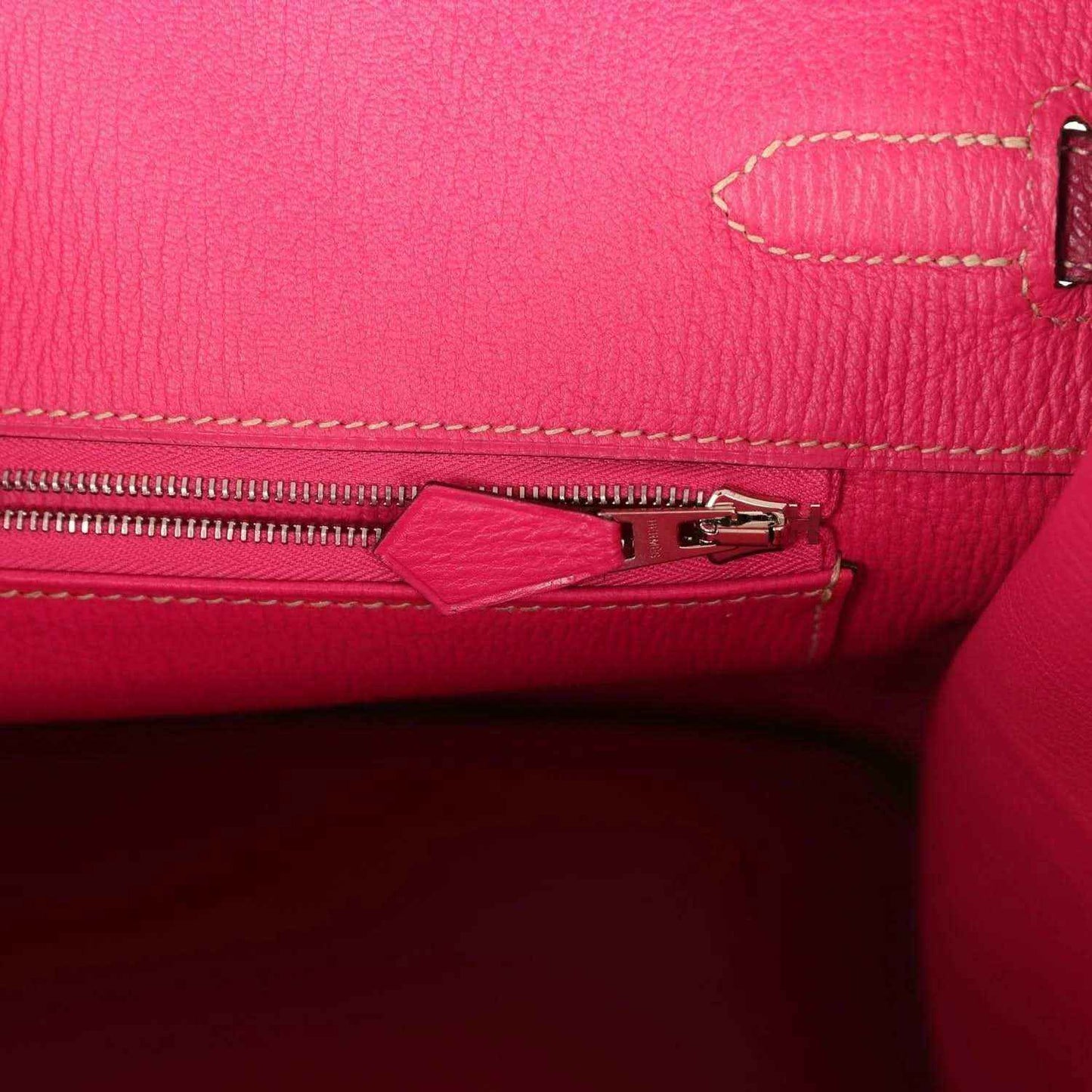 Pink leather interior with visible zipper track and metal slider, contrast stitching detail.