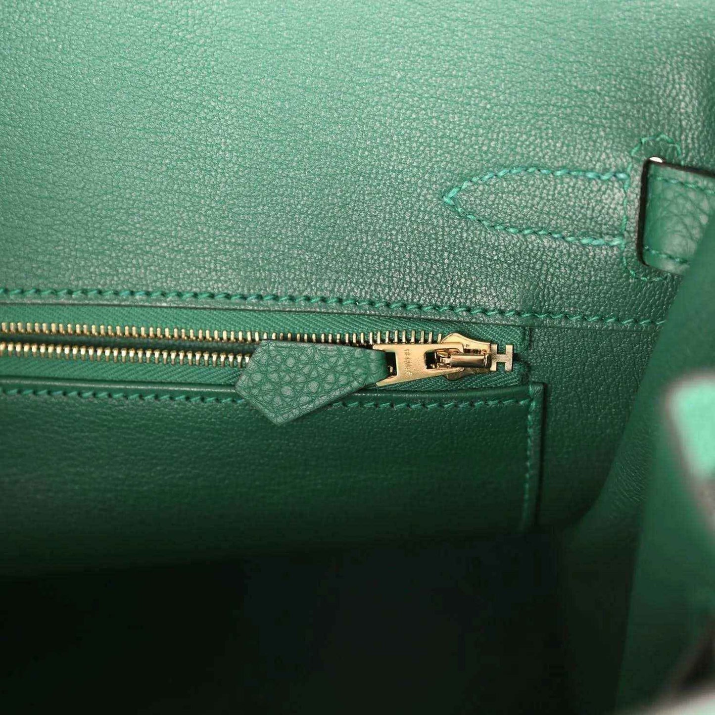 Green leather interior with gold zipper pull and stitched pocket divider