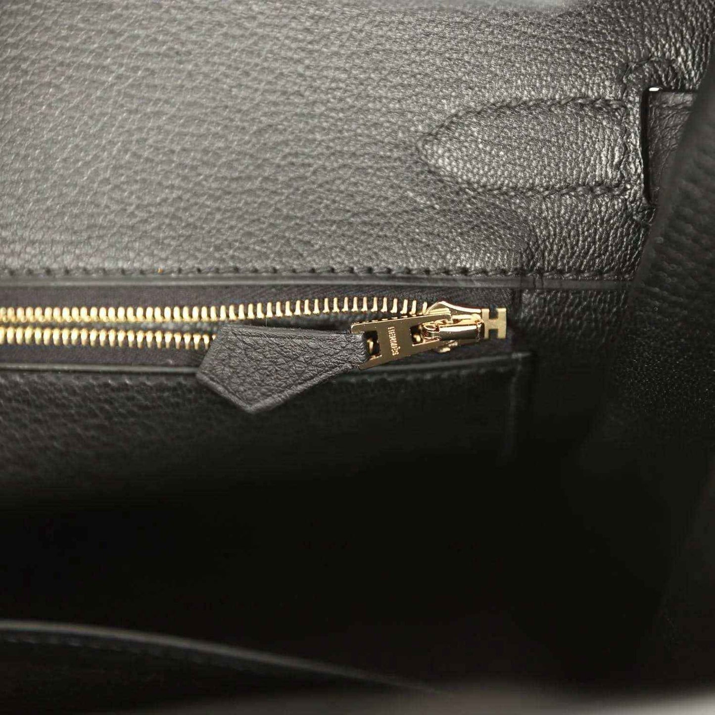 Black leather handbag interior with gold zipper and stitched pocket