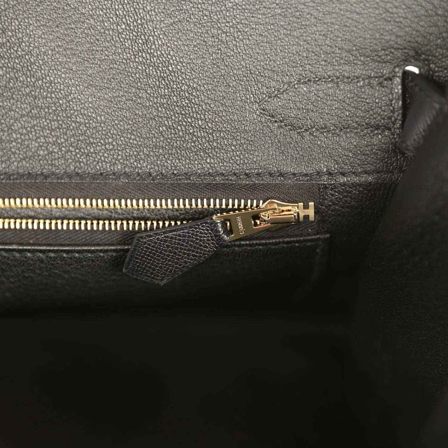 Black leather handbag interior with gold zipper pull and zipper track