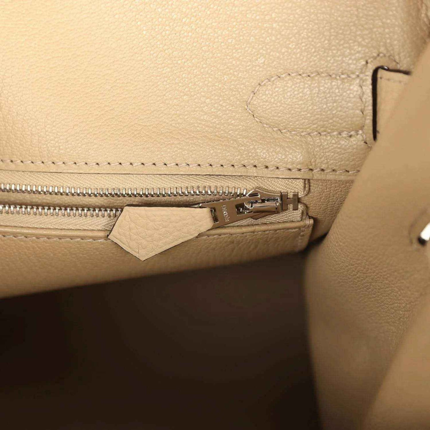 Tan leather handbag interior with zipper track and metal zipper pull