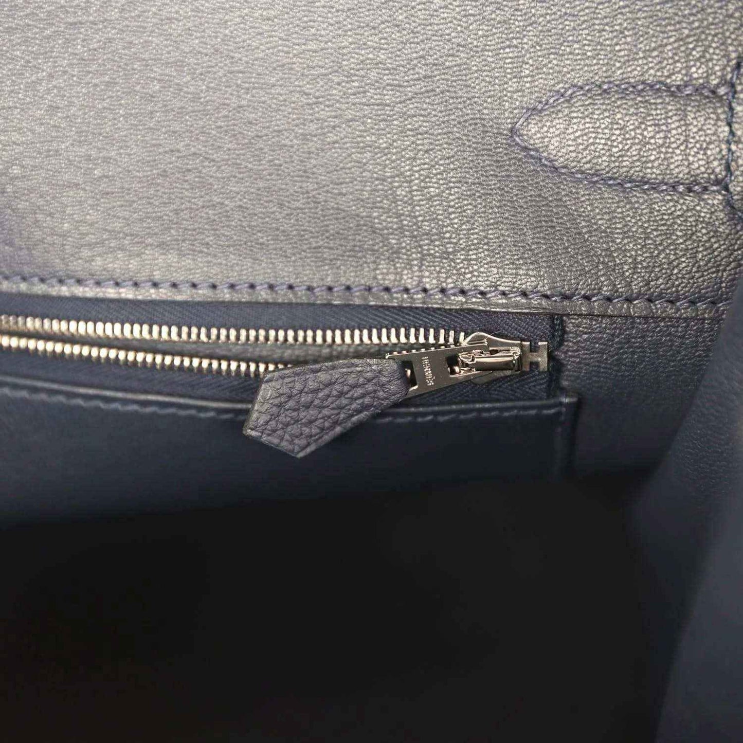 Navy leather handbag interior with zip pocket, zipper pull, and stitched trim