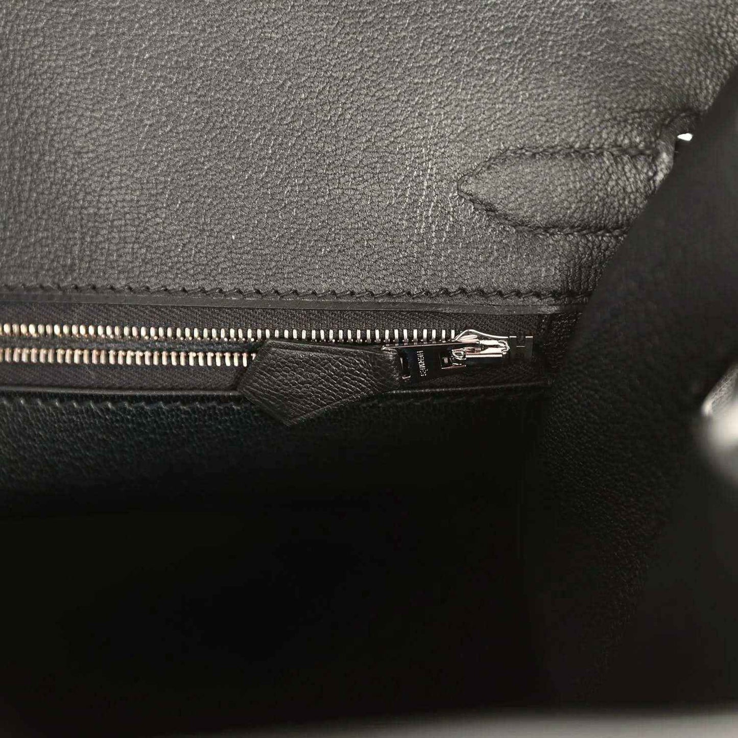 Black leather handbag interior with zipper and stitched fabric lining
