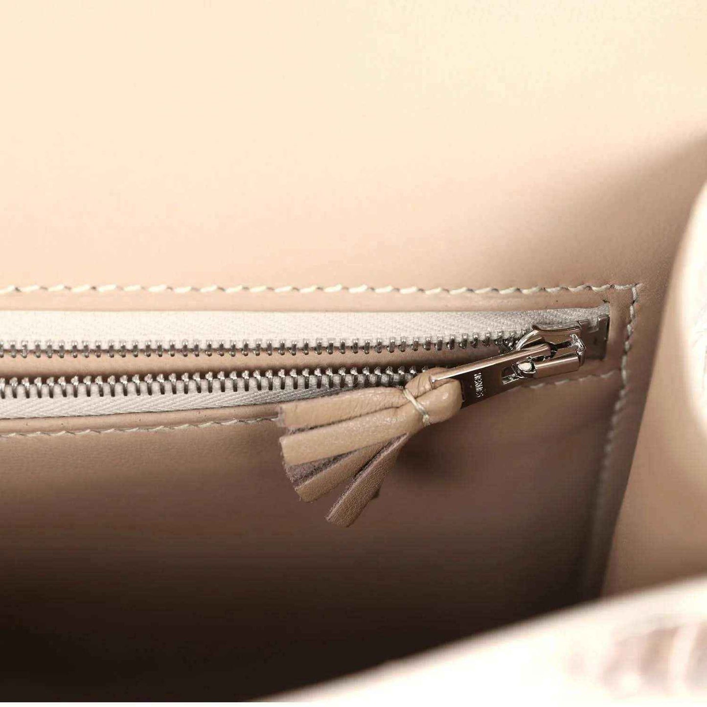 Constance-style bag interior close-up with zipper, metal pull, and tassel detail