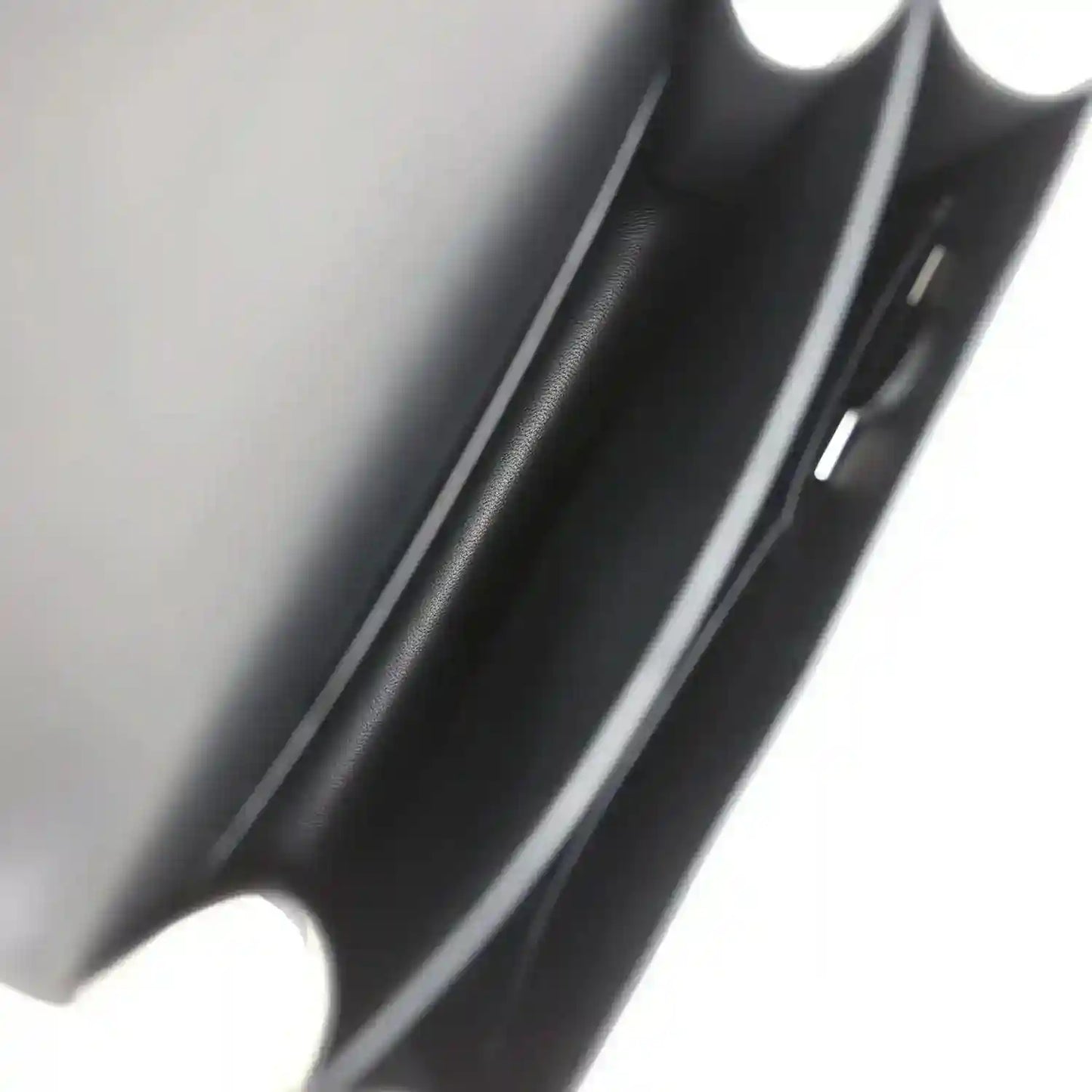 Black leather bag corner close-up with smooth grain and edge seam