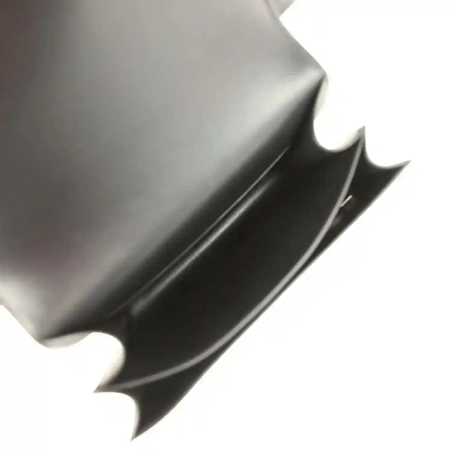Black handbag interior with smooth lining and open top-flap edge.