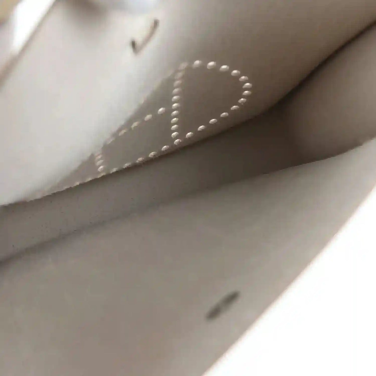 Light beige leather bag interior lining with stitched seam and logo-dotted detail