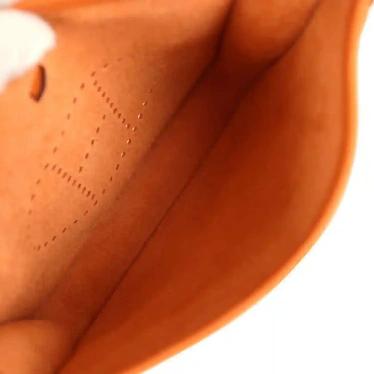 Orange leather interior of hobo bag with stitched lining and perforated 'E' detail