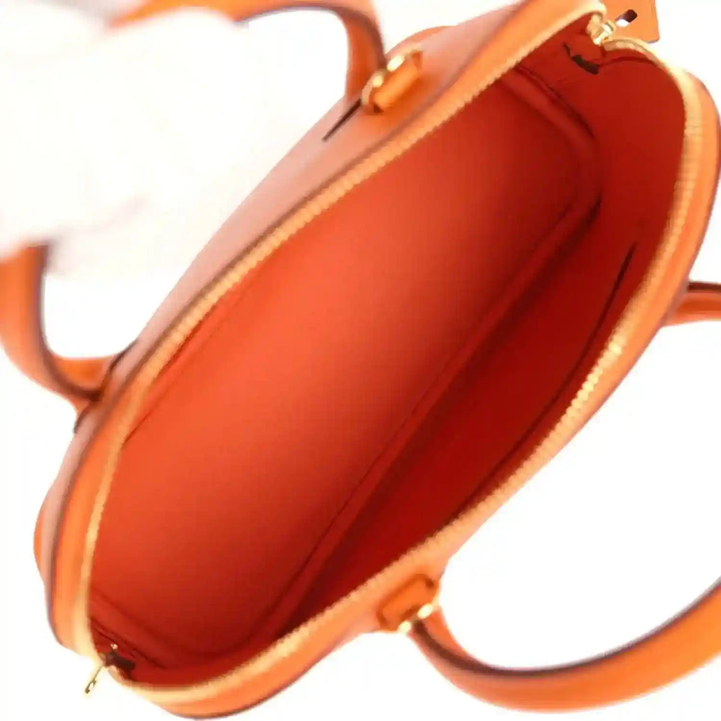 Orange leather interior view with zip opening and fabric lining, showing gold zipper trim.