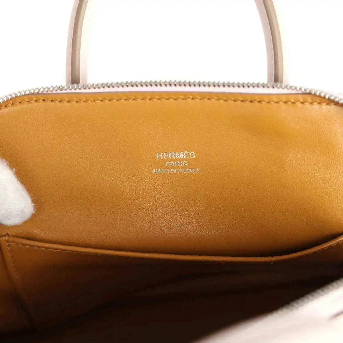 Tan leather interior of mini handbag with logo stamp under the zip