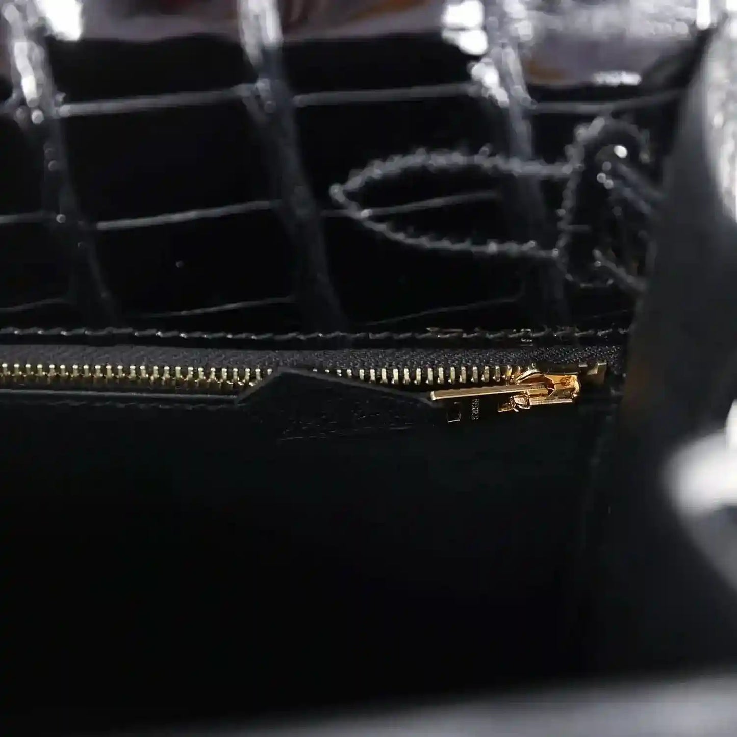 Gold zipper track and pull on black alligator leather handbag interior