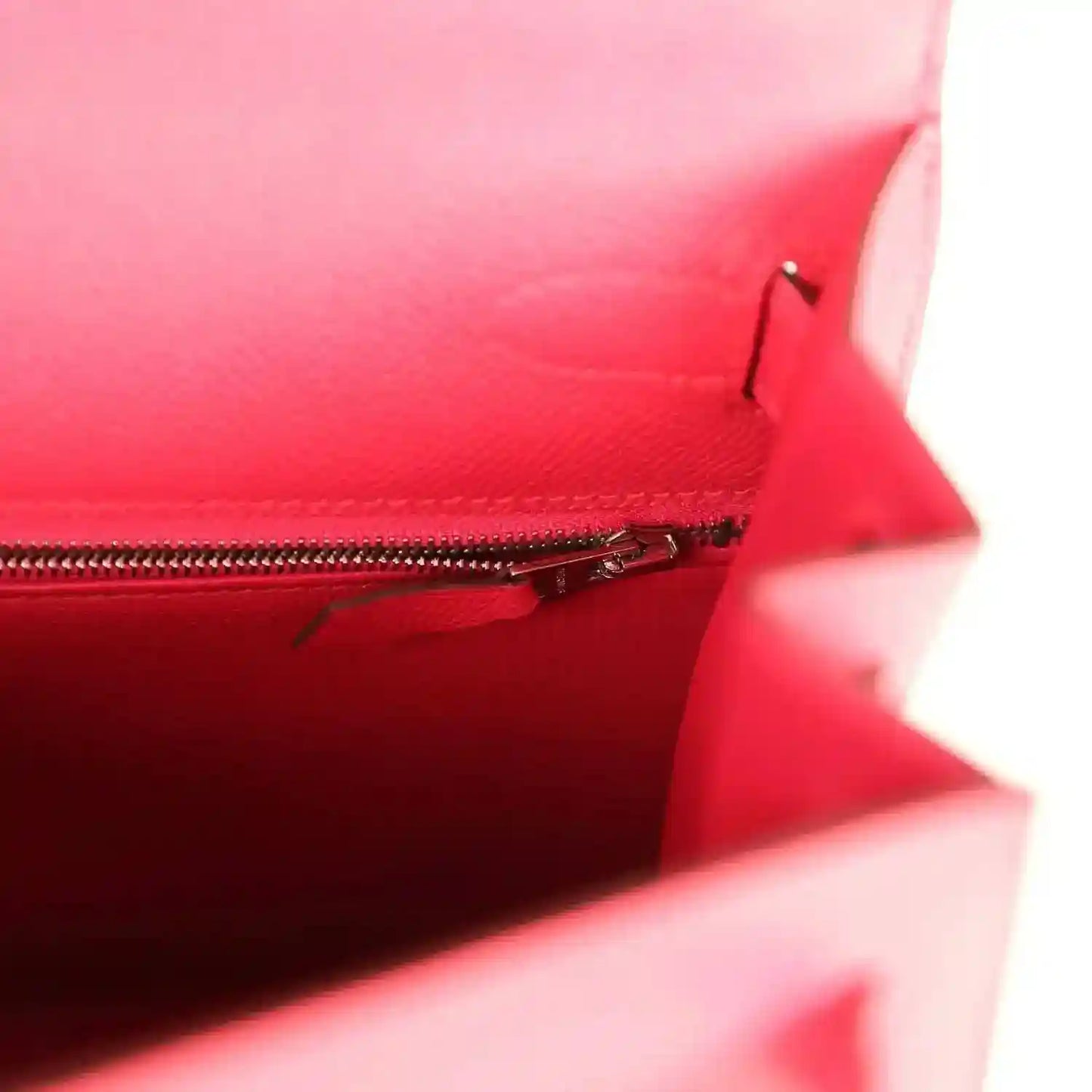 Red handbag interior with visible zipper track and small seam corner.