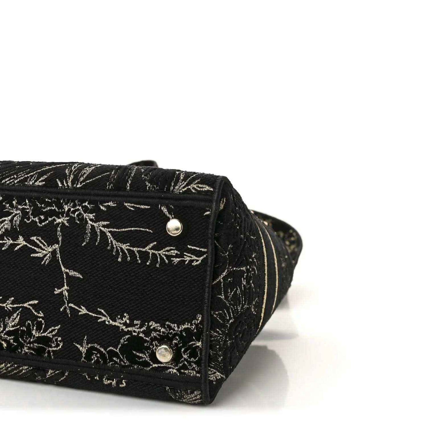 Close-up of black embroidered handbag bottom with gold button hardware