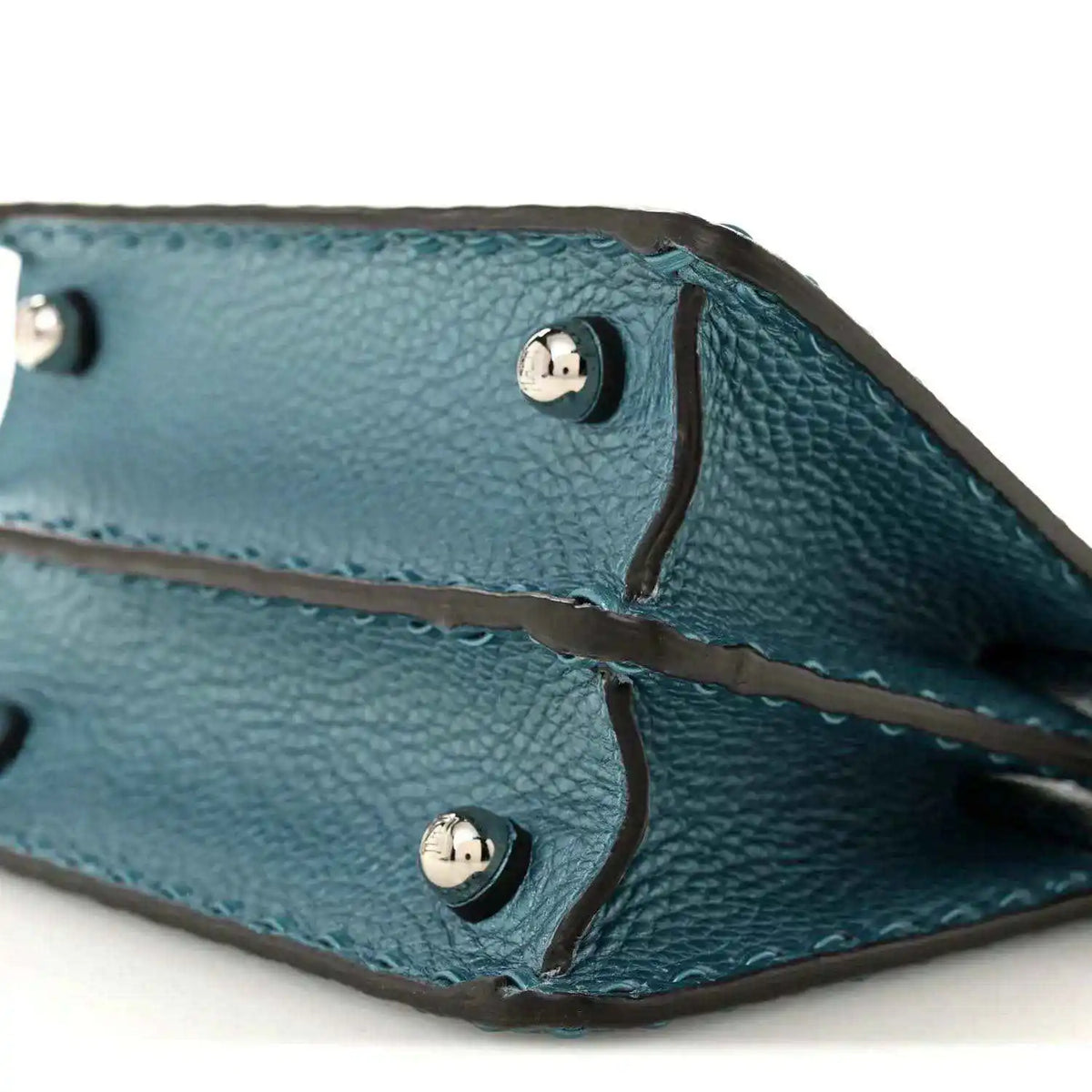 Blue leather satchel interior showing snap buttons and stitched leather tie straps.