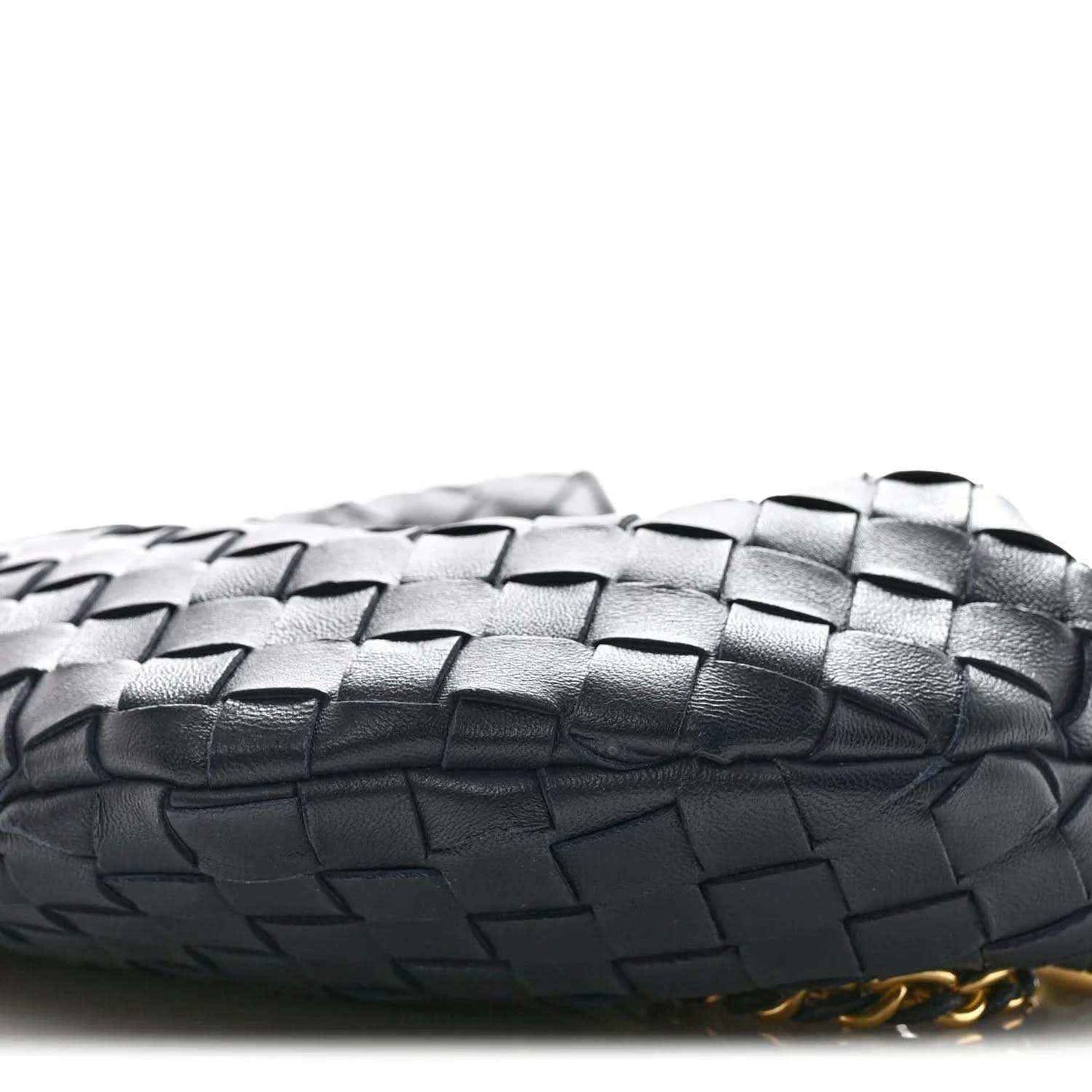 Close-up of light gray woven leather bag edge with gold chain detail