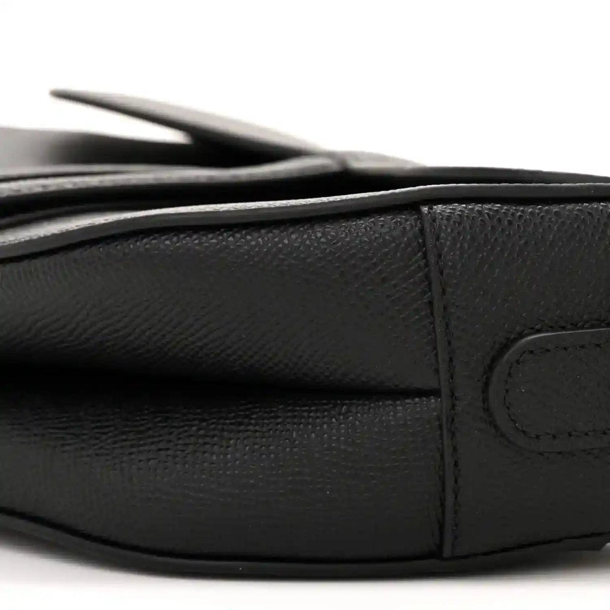 Black leather saddle bag corner with flap stitching and curved seam