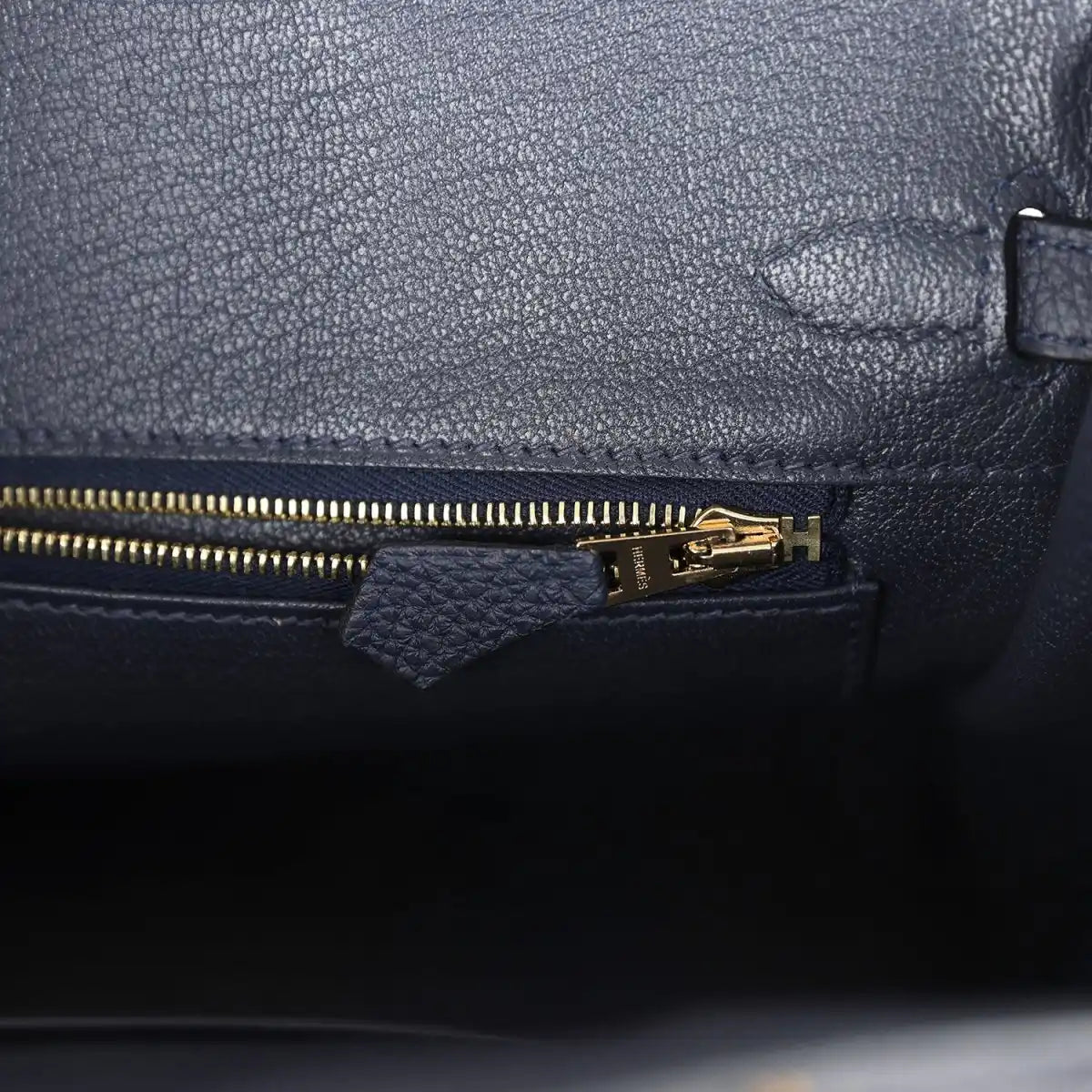 Hermes Birkin 25 handbag with dark blue leather zipper pocket and gold zipper pull.