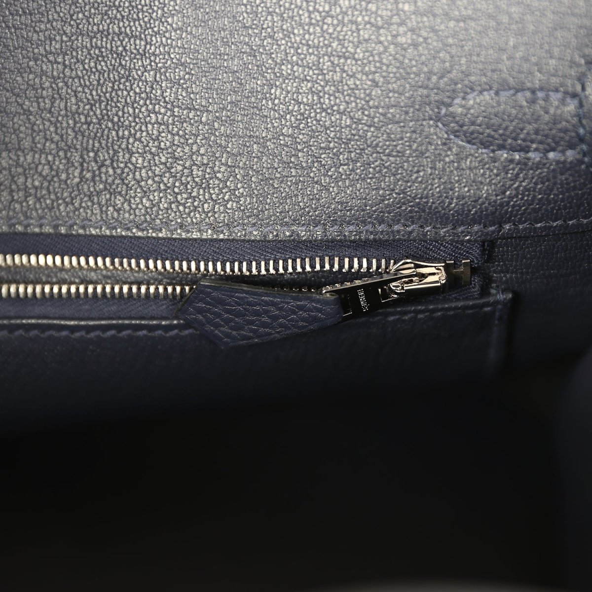 Birkin 25 handbag zipper close-up with dark blue lining and gold-toned pull