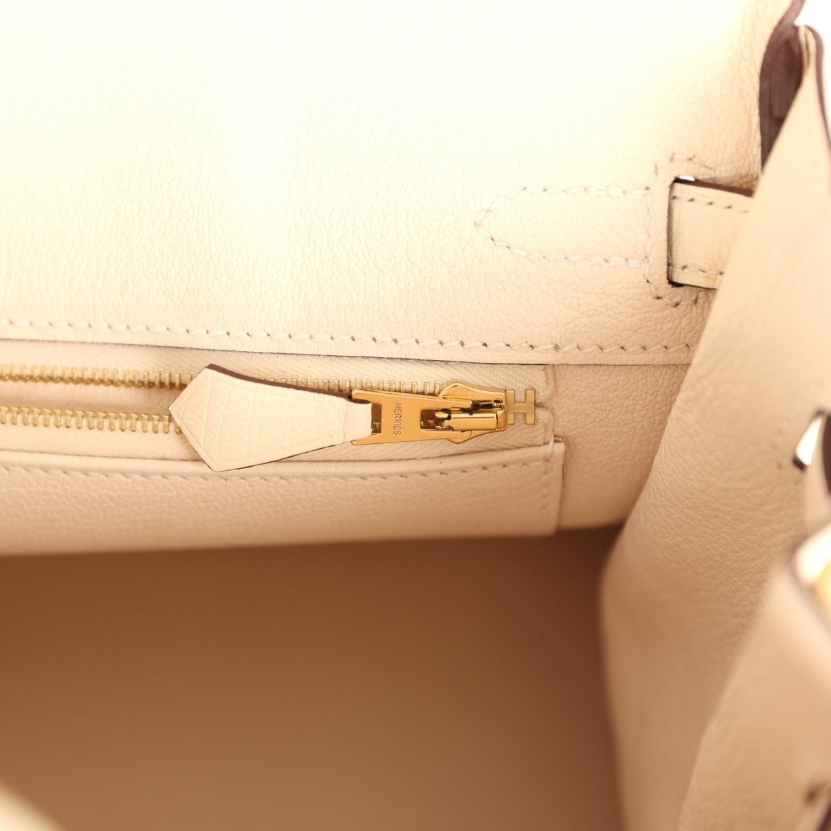 Nata ostrich handbag interior pocket with strap, gold-tone zipper pull, and stitching.