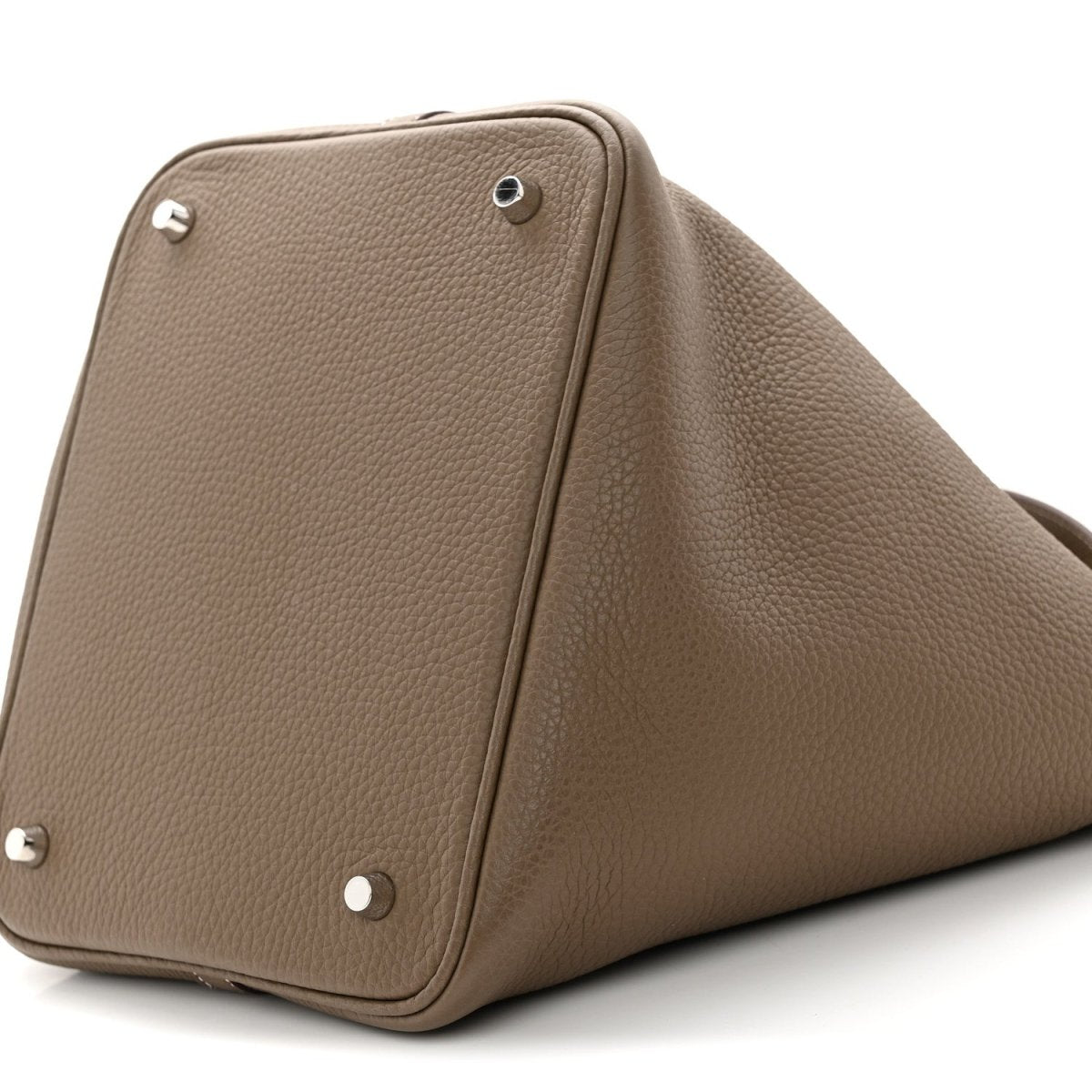 Taupe leather bucket bag side view with corner metal studs and textured grain.