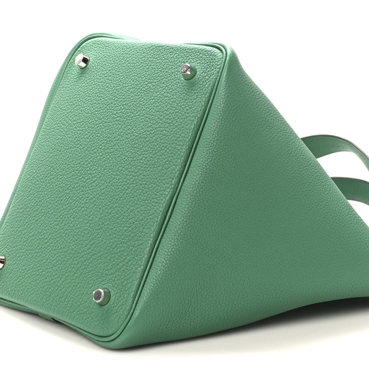 Green leather tote bag close-up with metal studs and seam along the edge