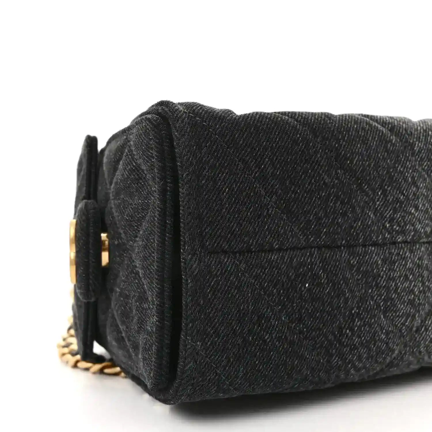 Black mini handbag side view with quilted texture and gold chain strap