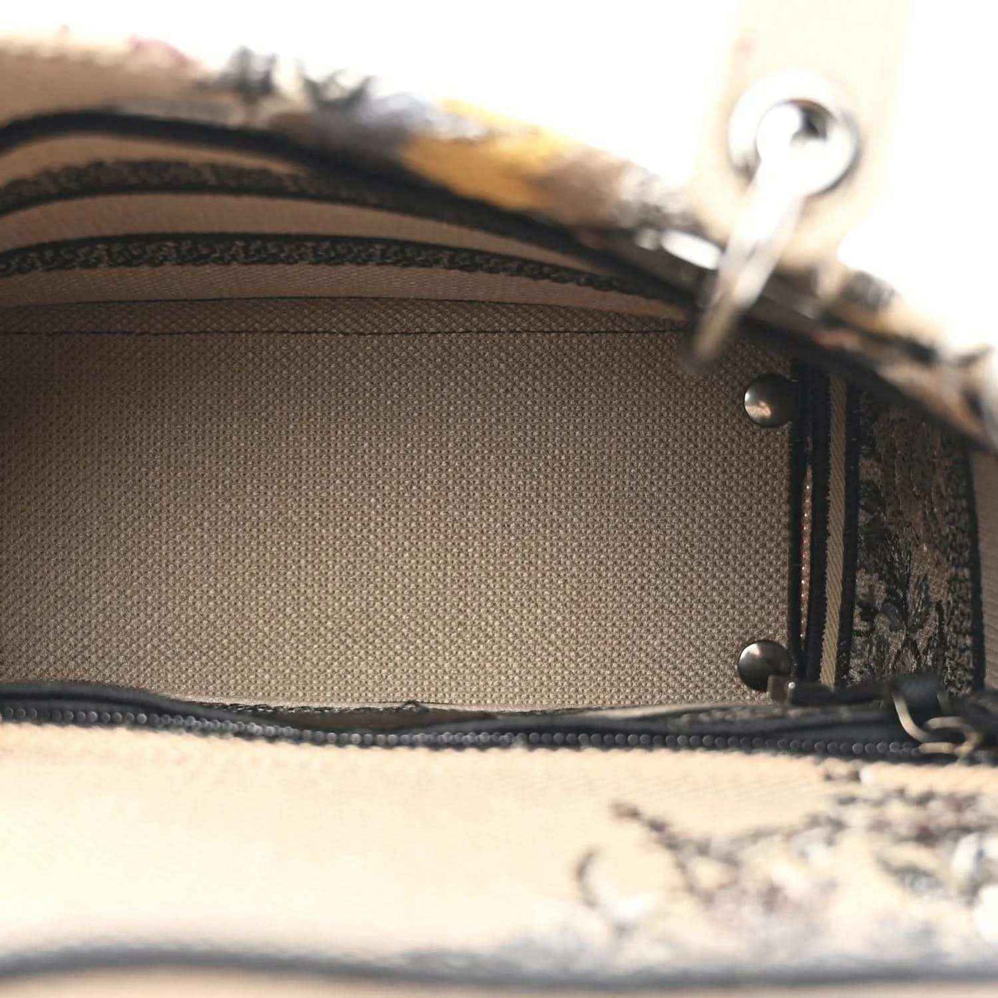Canvas bag interior lining with stitched edge and metal strap hardware.