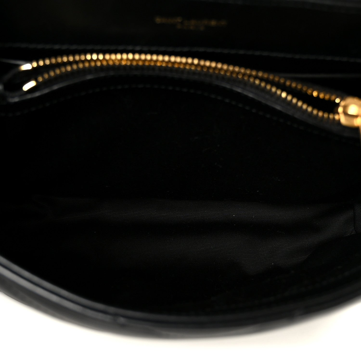 Black fabric lining of quilted chain satchel with gold zipper trim at the top.