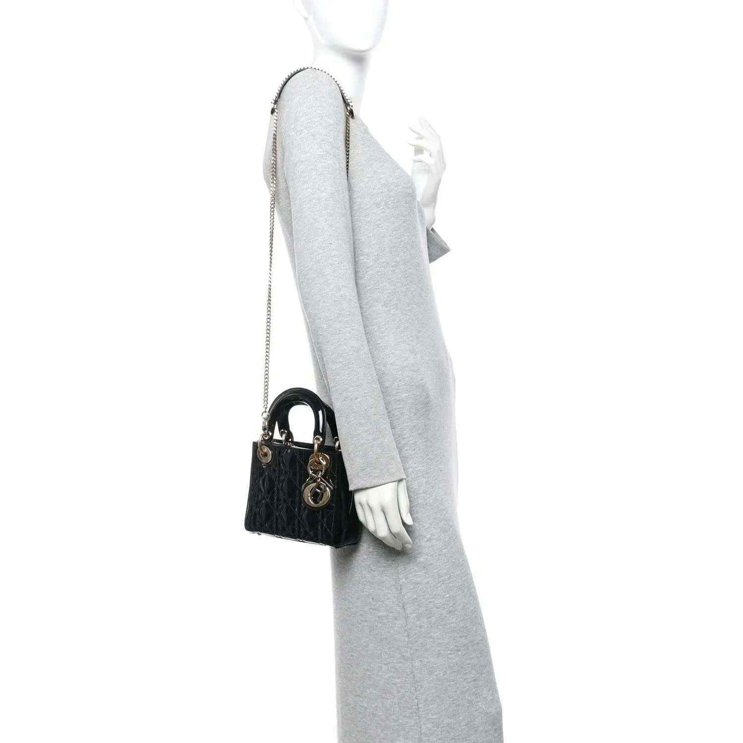 Black patent mini handbag with chain strap, worn on model shoulder, gold hardware