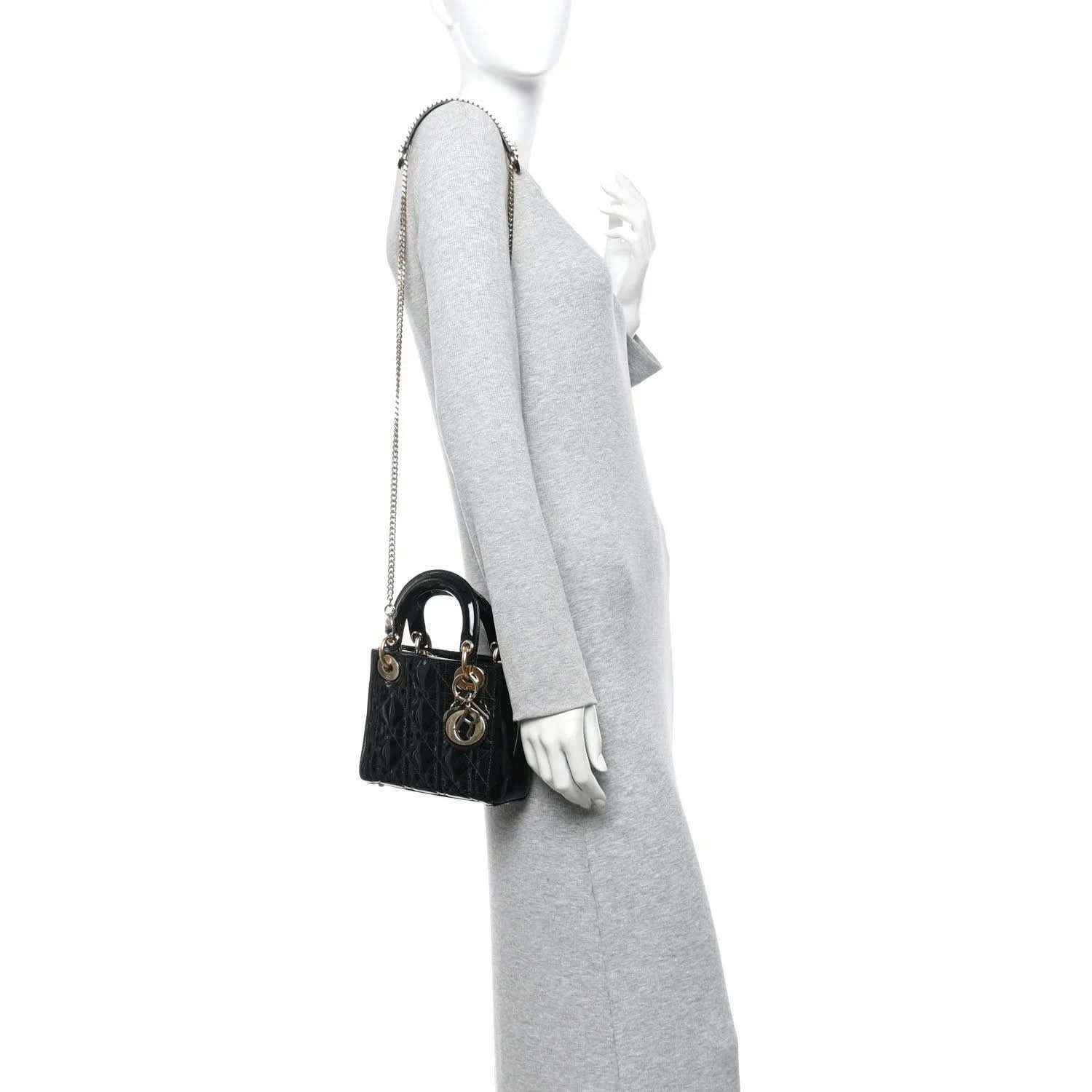 Black patent mini handbag with chain strap, worn on model shoulder, gold hardware