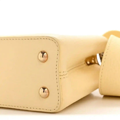 Cream mini handbag corner with round metal studs and interior edge view.
