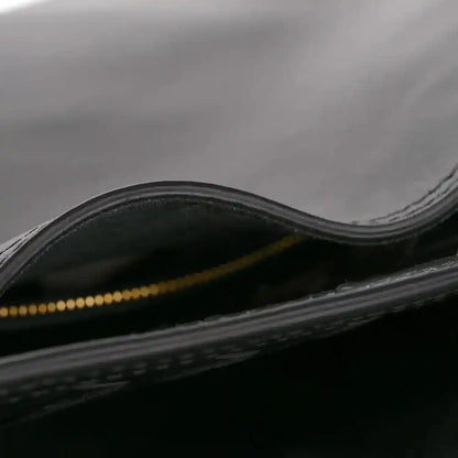 Black bucket bag with gold-tone zipper and leather trim, view of opening