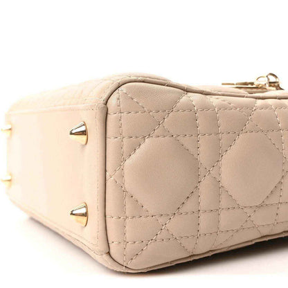 Beige quilted mini handbag side with gold studs and stitched panel seams