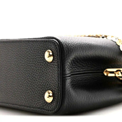 Black leather handbag corner with two gold-tone snap studs and inner zipper edge