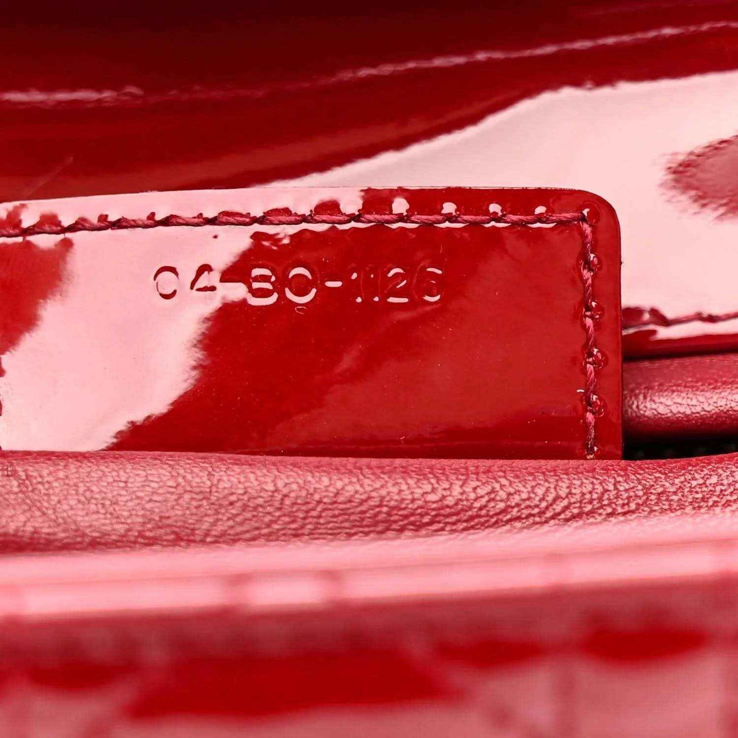 Red leather date code stamp on interior panel with stitched edge.