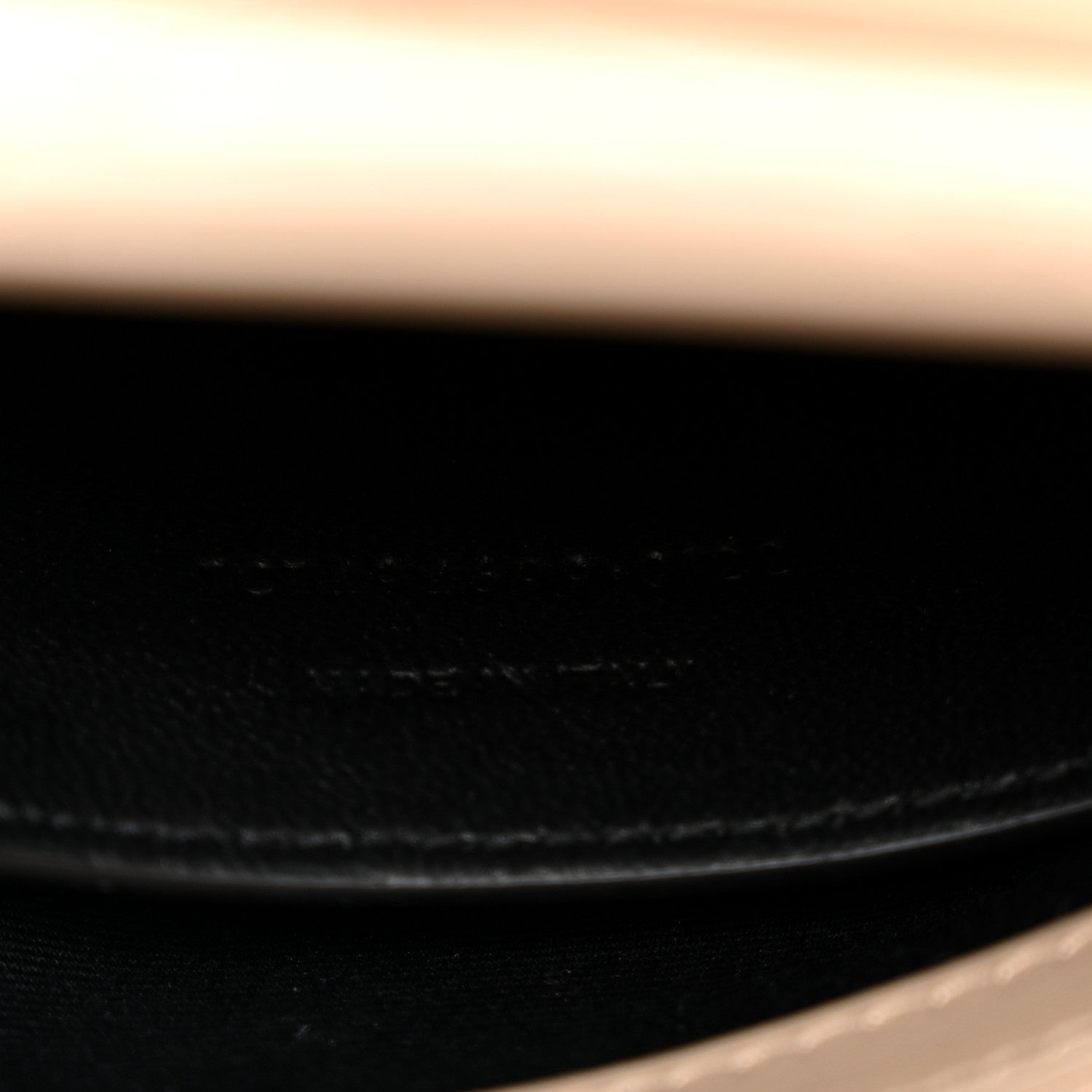 Dark leather interior seam close-up with stitched edge and gold chain attachment