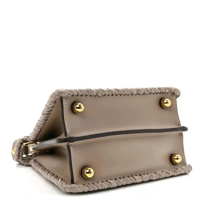 Light gray leather flap satchel with gold snap buttons and raffia trim